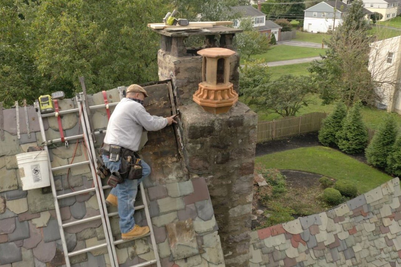 roofer repairing chimney flashing on a slate roof in King of Prussia Pa